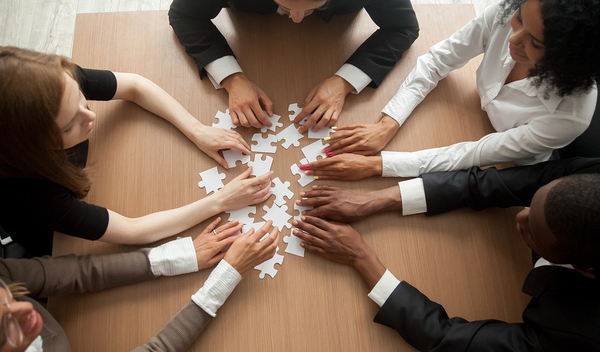 Group of employees sitting around a table building a puzzle together.